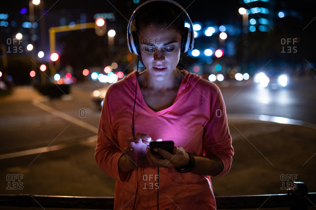 Woman runner in jogging outfit running on a street. Woman listening to  music using earphones while running Stock Photo - Alamy