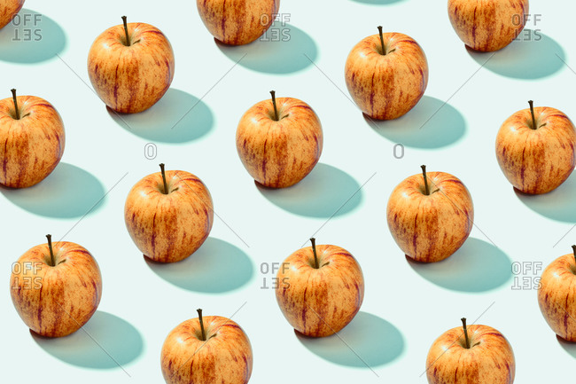 Pattern background of red apples on cyan background. Vibrant colorful pattern