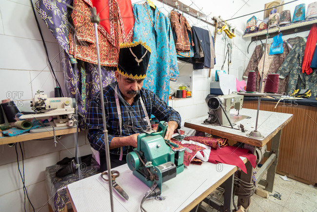 March 5, 2019: An elderly tailor man in a using a sewing machine. Yazd, Iran
