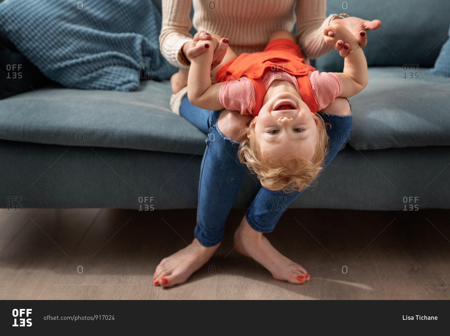Happy baby playing on mother\'s lap with head upside down