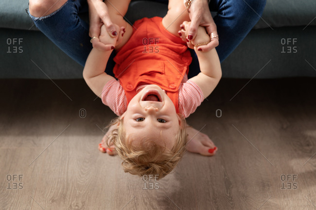 Laughing baby playing on mother\'s lap with head upside down