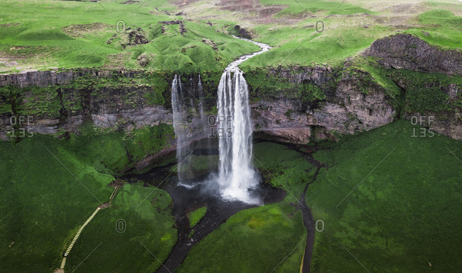Aerial view, Seljalandsfoss waterfall falls from high cliff, green grass landscape, South Iceland, Iceland, Europe