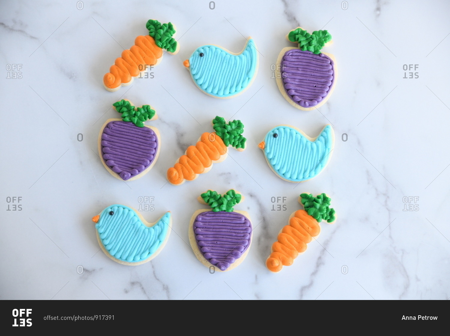 Overhead view of colorful bird, carrot and turnip Easter cookies on marble surface