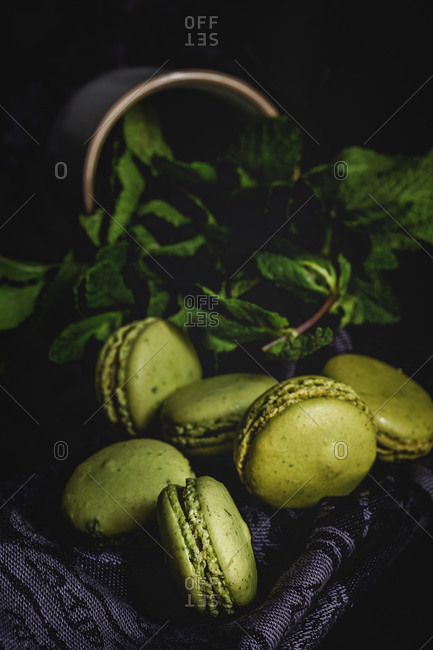 Homemade green macarons green with mint on dark background. Dark food.