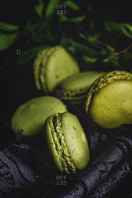 Homemade green macarons green with mint on dark background. Dark food.