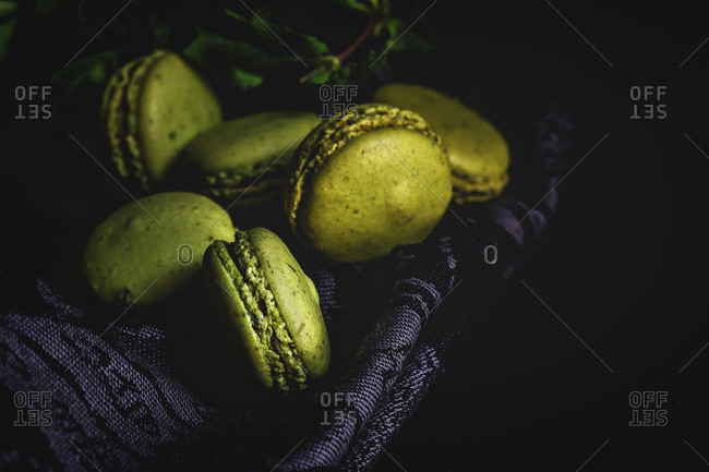 Homemade green macarons green with mint on dark background. Dark food.