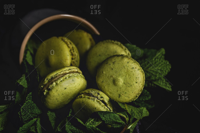 Homemade green macarons green with mint on dark background. Dark food.