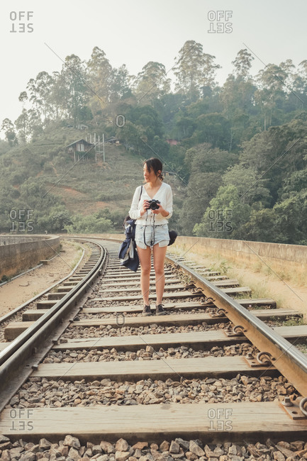 Female tourist walking on lonely railway against exotic forest
