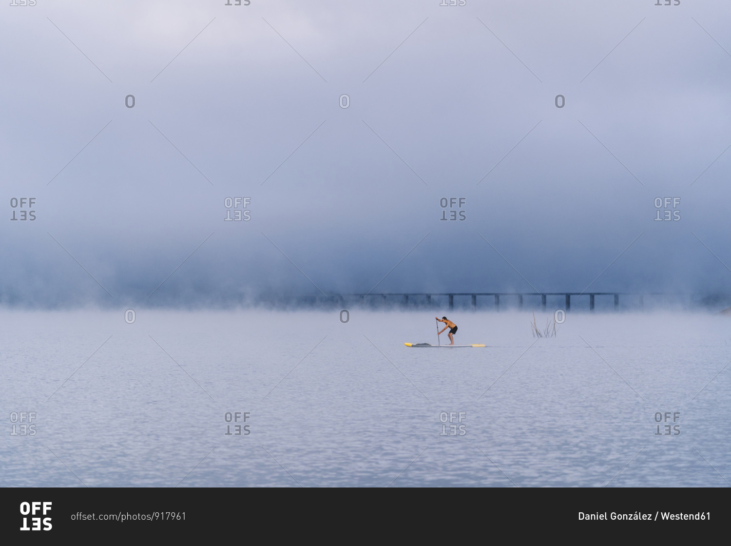 Man stand up paddle surfing on a lake in the fog