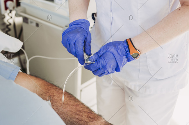 Nurse adjusting iv drip for patient lying in hospital bed