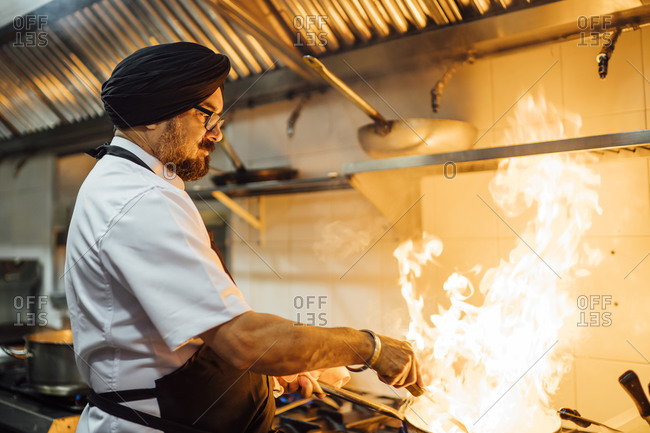 Indian chef flaming food in restaurant kitchen