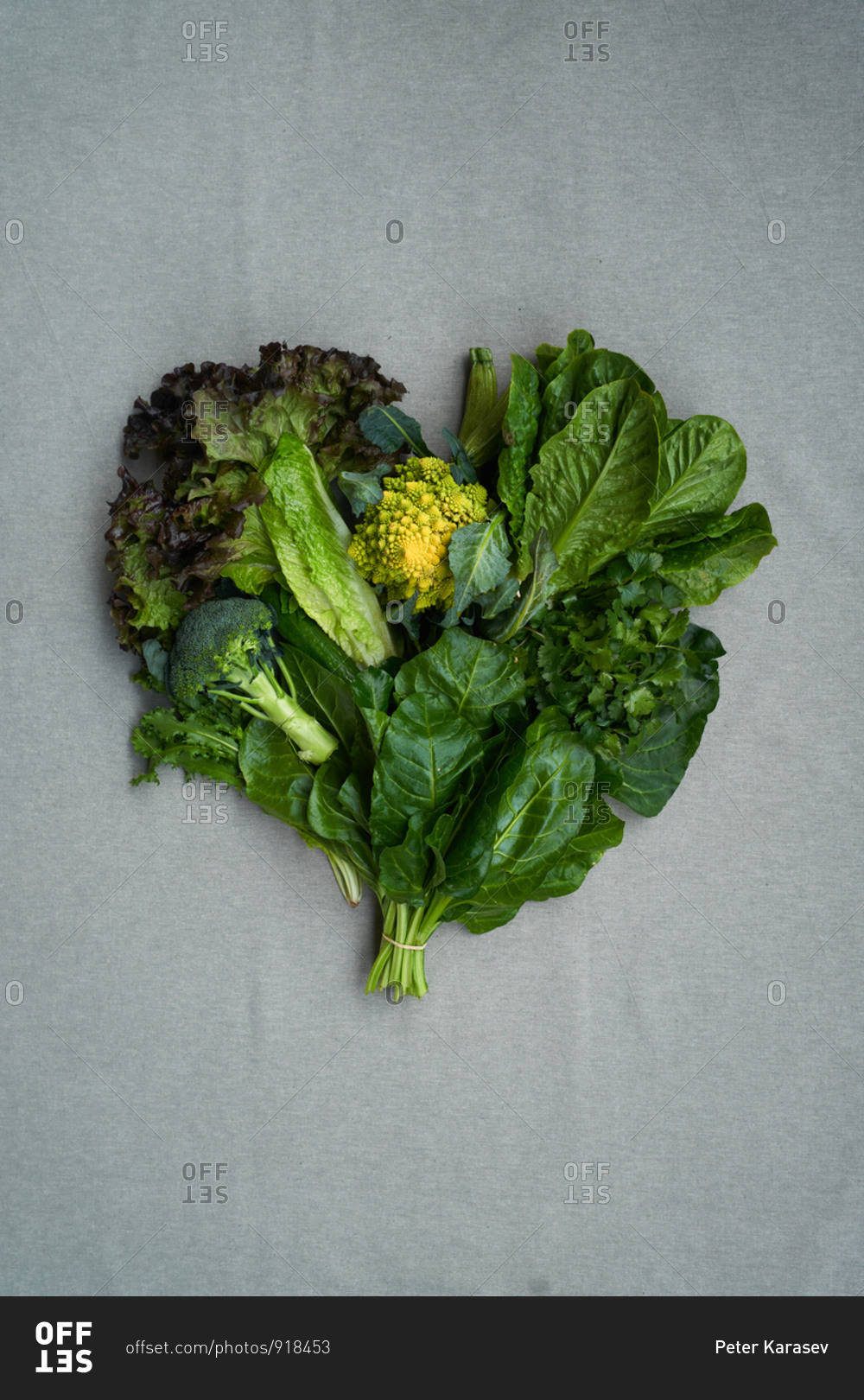 Heart shaped bunch of lettuce leaves and broccoli on gray background