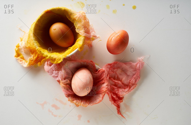Top view image of colorful painted eggs and gauze clothes on neutral background with negative space