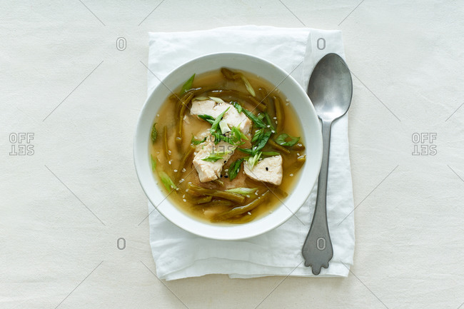 Miso soup with green beans and chicken on textile background