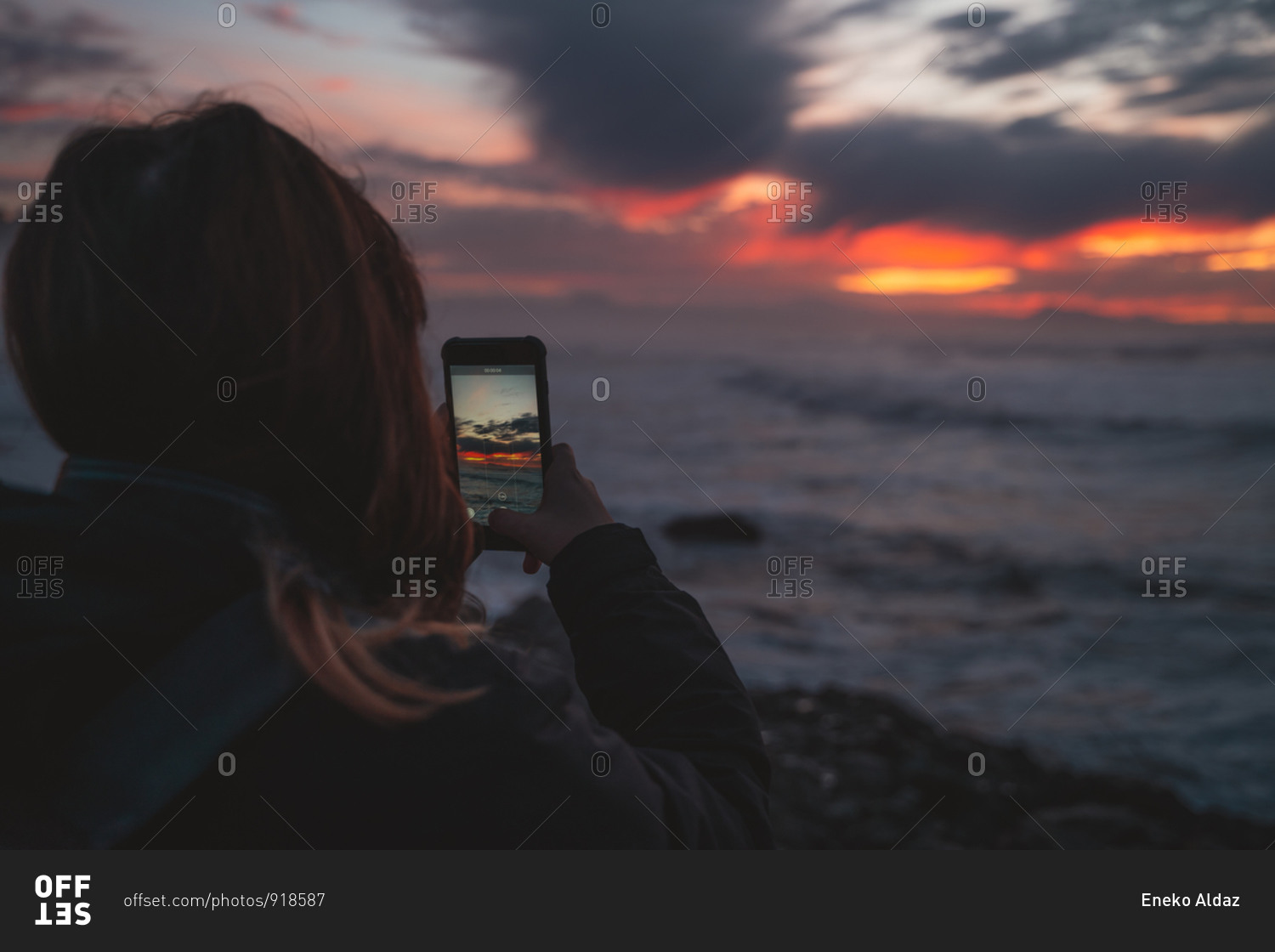 Girl taking a photo of the sunset on her smart phone
