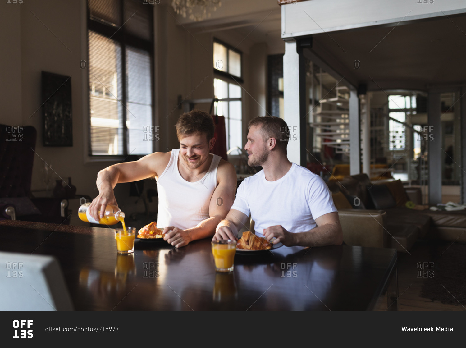 Front view of Caucasian male couple relaxing at home, sitting by the table, eating breakfast together