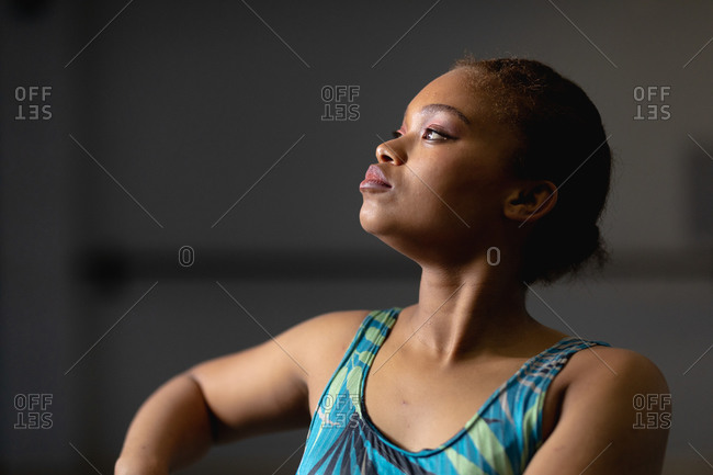 Side view close up of a mixed race female dancer wearing blue floral dress and rising her arms while dancing.