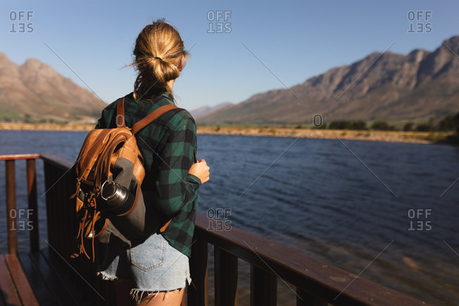 Rear view of a Caucasian woman having a good time on a trip to the mountains, standing on a cabin balcony, enjoying her view, on a sunny day