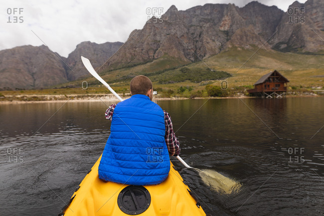 Rear view of a Caucasian man having a good time on a trip to the mountains, kayaking on a lake, enjoying his view