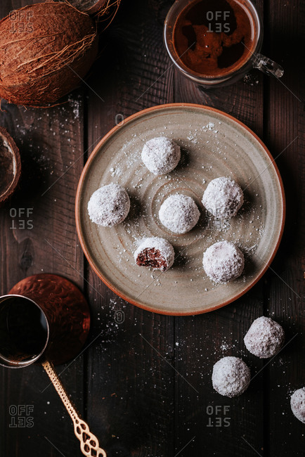 Raw coconut and dates balls with homemade coffee on a rustic wooden table