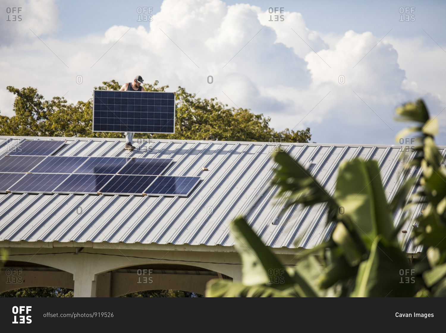 Construction worker carries solar panel on rooftop during install.