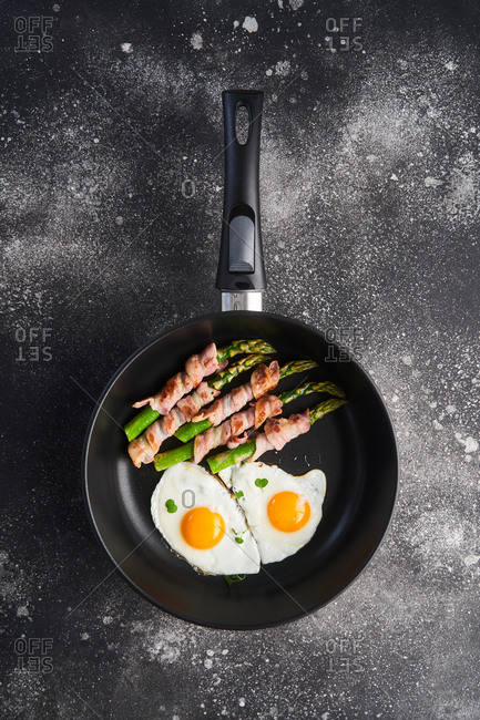 Sunny Side Up Fried Eggs In Heavy Duty Teflon Frying Pan With Pork Bacon  Rashers On Cutting Board Set On Old Cracked Wooden Picnic Table Stock Photo