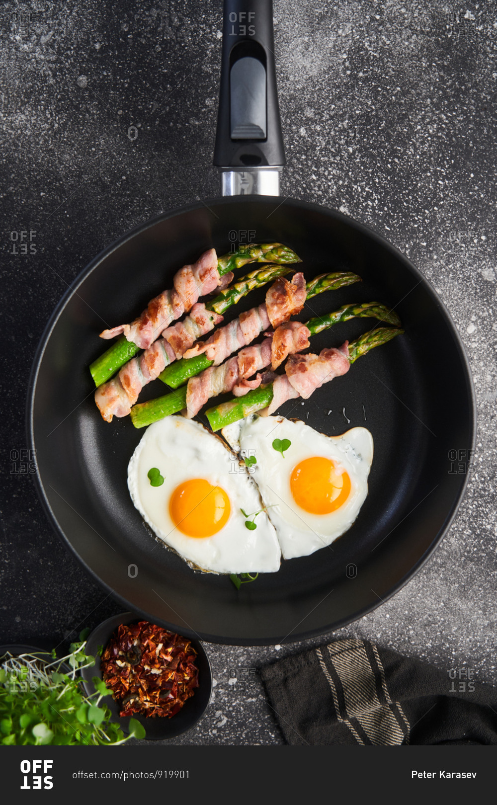 Overhead view of bacon wrapped asparagus with fried eggs in a skillet