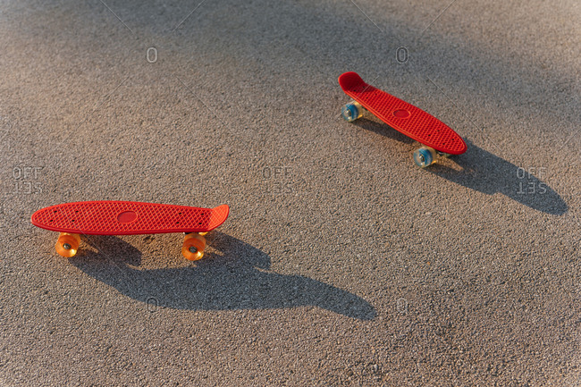 Two red skateboards on a concrete background