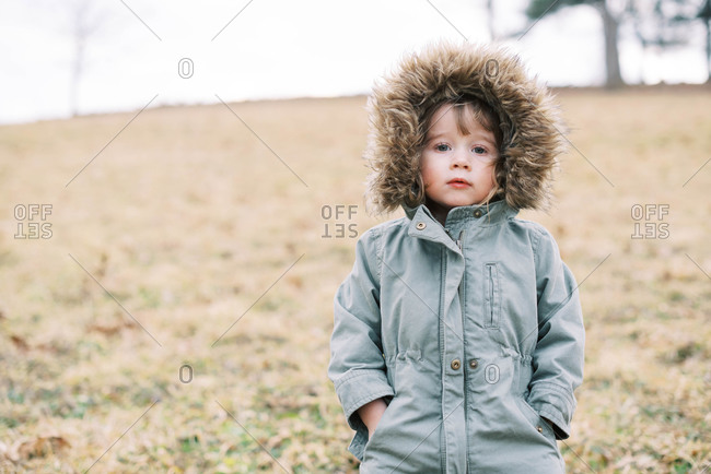A kid walking through a mowed meadow in winter.