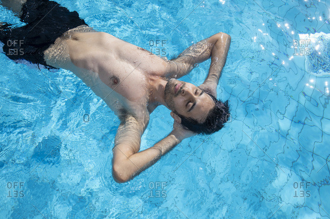 A man or a boy is swimming or floating in a swimming pool