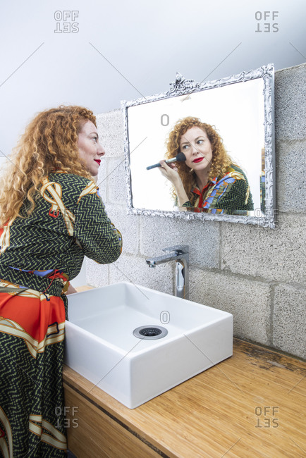 An adult woman looking at her mirror image in the bathroom