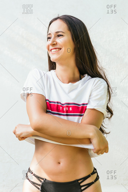 Portrait of a pretty young woman taking off a shirt in summer.