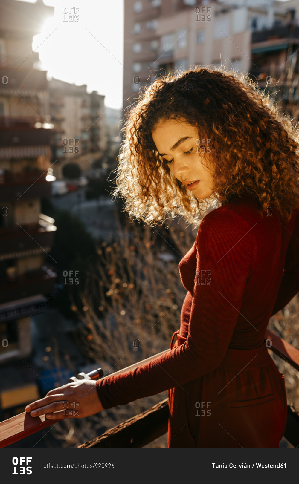 Portrait of young woman wearing red turtleneck pullover- standing on balcony