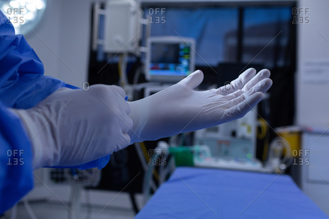 Mid section of Caucasian male surgeon wearing medical gloves in operation theater at hospital