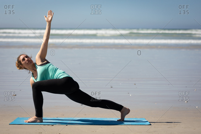 Slim woman doing pose on yoga mat stock photo - OFFSET