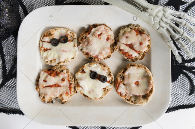 Plate of mini pizzas and hand of Halloween skeleton