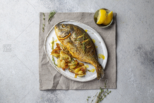 Grilled sea bream or dorada on gray plate. Gray background.