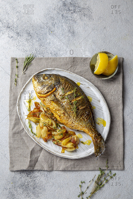 Grilled sea bream or dorada on gray plate. Gray background.