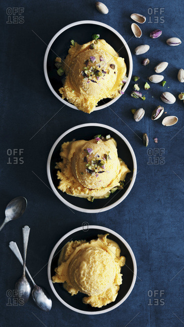 Scoops of apricot and pistachio nut ice cream in serving bowls.