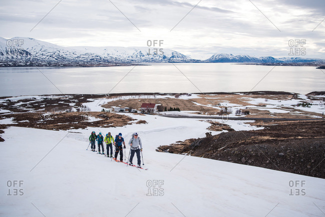 A group backcountry skiing in Iceland with the ocean in the background