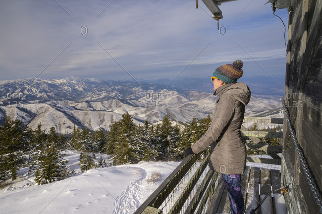 Female Looking Into The Distance From A Fire Lookout In The Mountains