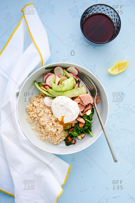 Breakfast bowl with oatmeal, poached egg, tuna and greens