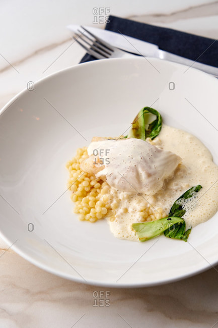 White fish fillet served over ptitim with classic French butter sauce