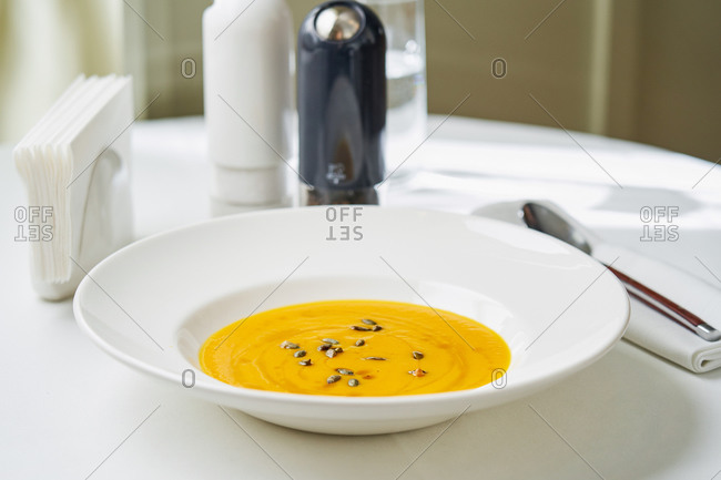 Cream of pumpkin soup with pumpkin seeds on white round table