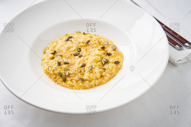 Creamy pumpkin risotto topped with parmesan cheese and pumpkin seeds