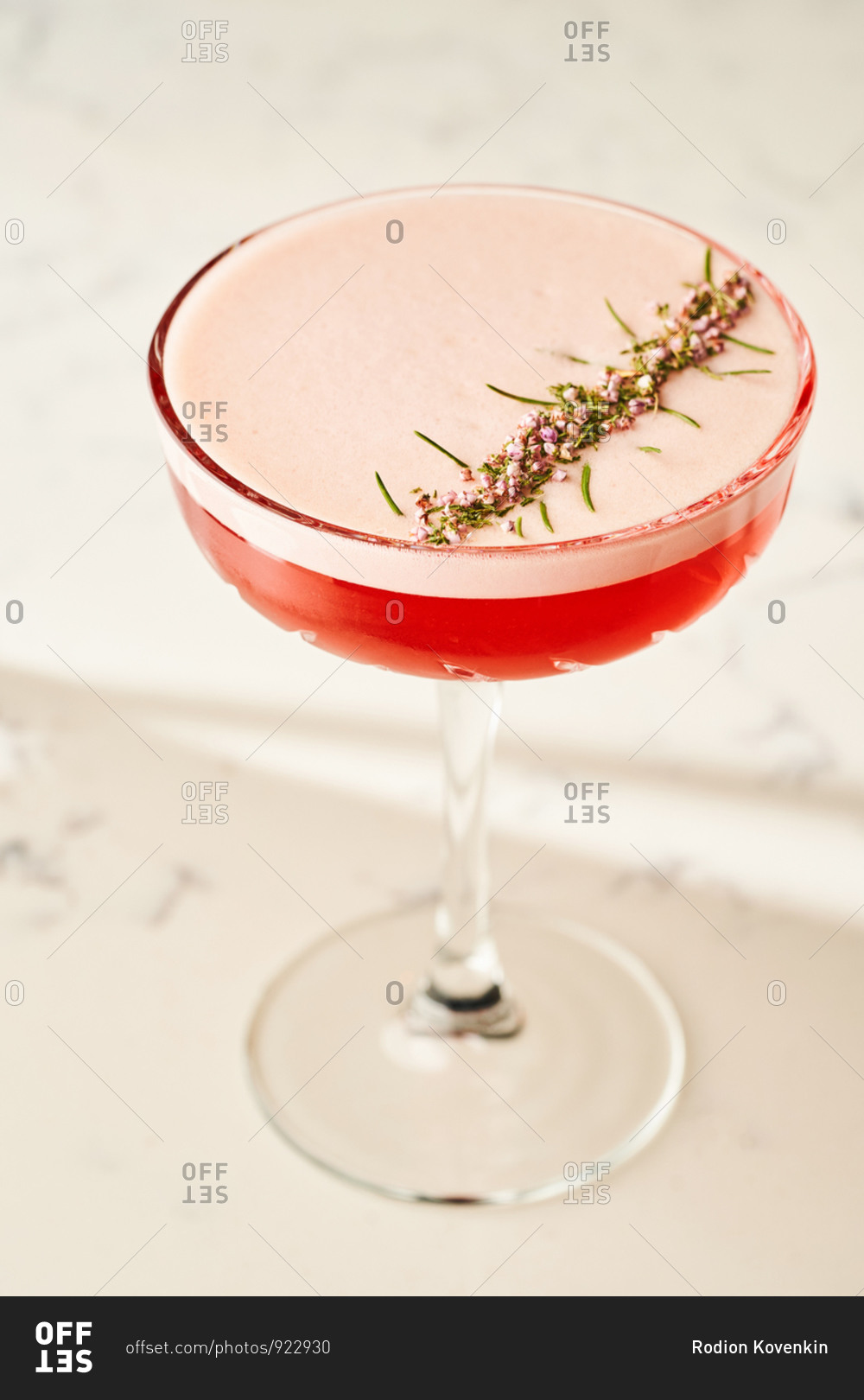 Beautifully garnished pink lady cocktail on white marble bar countertop