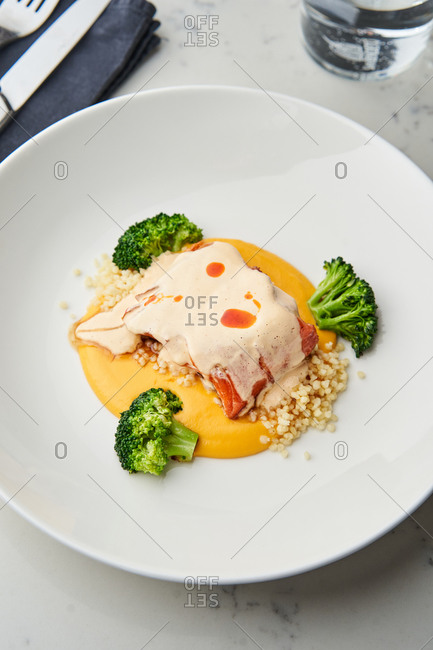 Salmon fillet with sweet potato puree, couscous and broccoli on white table