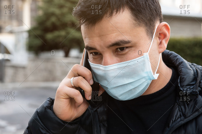 Man wearing protective face mask and calling phone