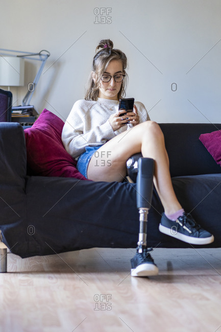 Young woman with prosthetic leg using smart phone by female friend