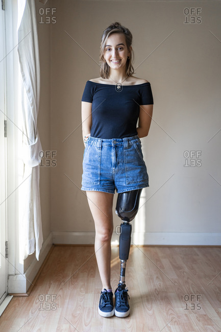 Disabled young woman with prosthetic leg standing in front of a